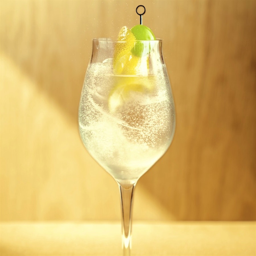 A gin spritz cocktail in a wine glass with a lemon rind twist and olive on a stick